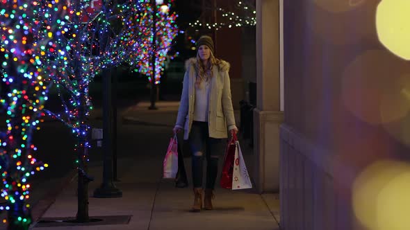 Young pregnant woman walking past trees with Christmas lights alt