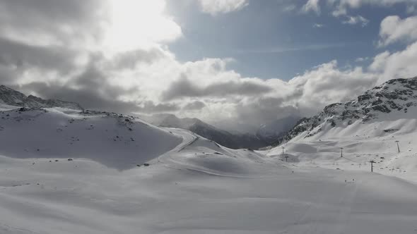 Winding Trail Through Rugged Snow Covered Mountain Peaks in Winter with the Sun Peeping Through  alt