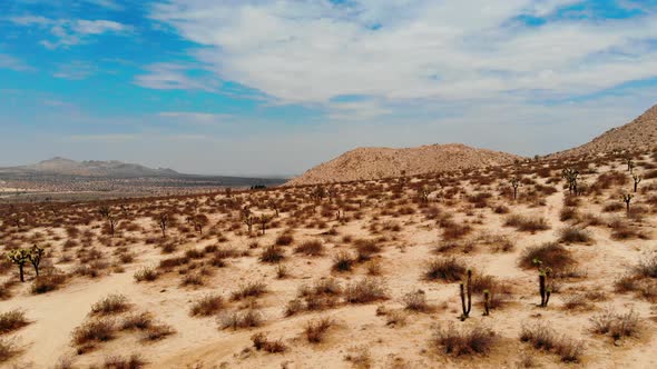 Flying low over the desert in Joshua Tree in california with Rocky mountainous barren terrain during alt
