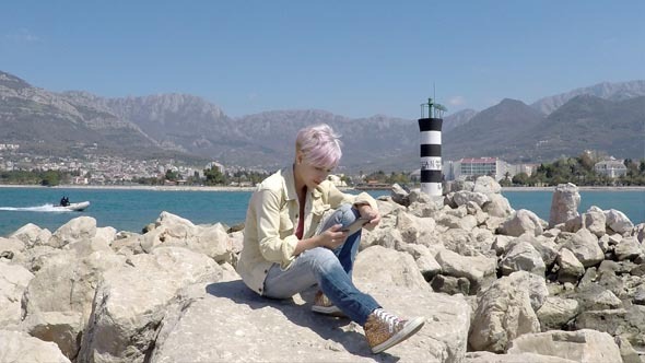 Woman Reads Electronic Book Near the Lighthouse