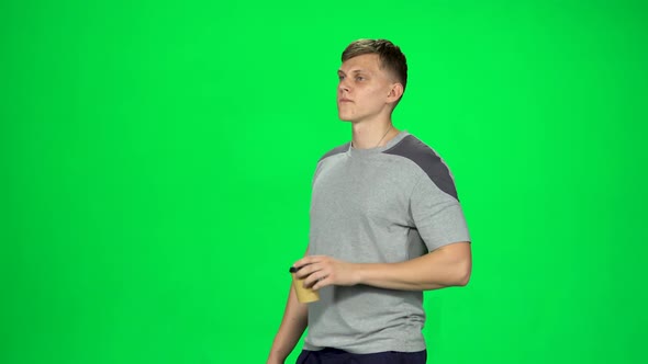 Male Is Walking and Drinking Coffee From a Paper Cup alt