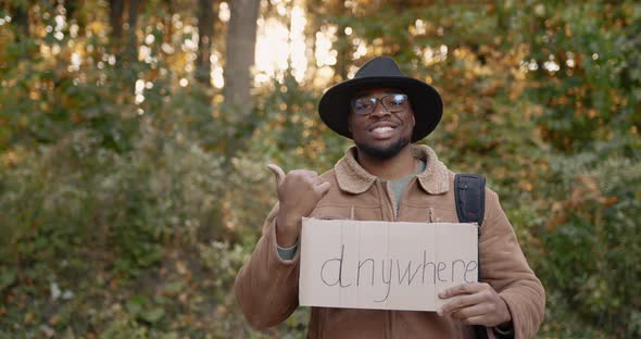 Black Hitchhiker with a Sign in His Hands on the Roadside alt