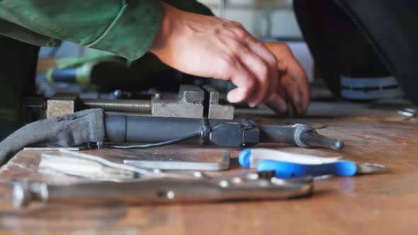 Close Up of Male Arms of Mechanic Taking and Examining Some Vehicle Detail at Workshop alt