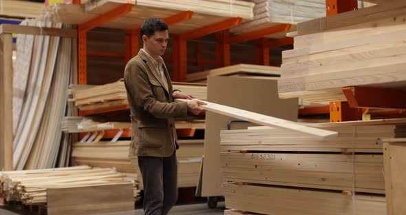 Man Chooses Wooden Planed Boards Products in the Market