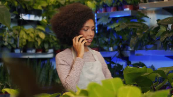 African woman florist talking by phone alt