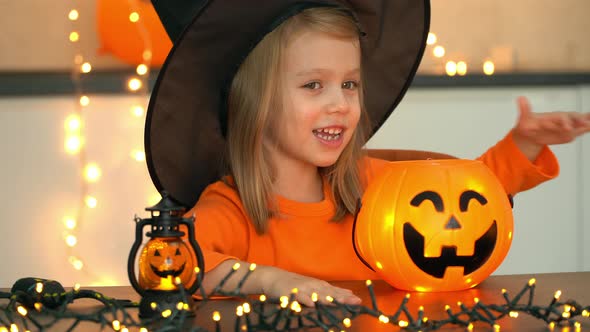 Happy Girl in Witch Costume Fun Casts Spell Over Shining Pumpkin