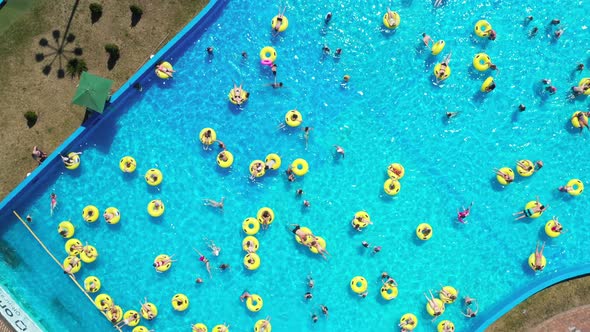 Top View of People Relaxing in the Pool on Yellow Inflatable Circles