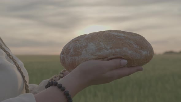 Closeup of a Loaf of Freshly Baked Homemade Bread in a Woman's Hands in a Field alt
