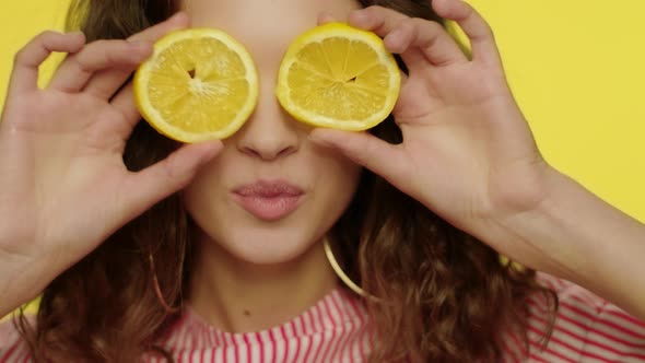 Young Woman Kissing Lips with Lemon Slices in Front of Eyes alt