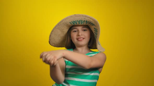 Cute Cheerful Little Girl in the Straw Hat is Dancing in a Yellow Background alt
