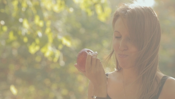 The Girl Eats a Red Apple In The Forest