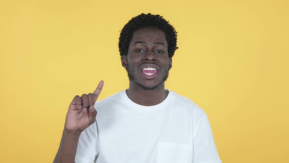 African Man Waving Finger to Refuse Yellow Background alt