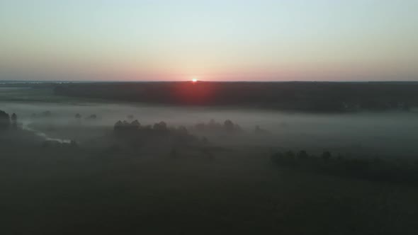 Foggy dawn in the countryside. Foggy river valley and rising sun. Aerial photography.