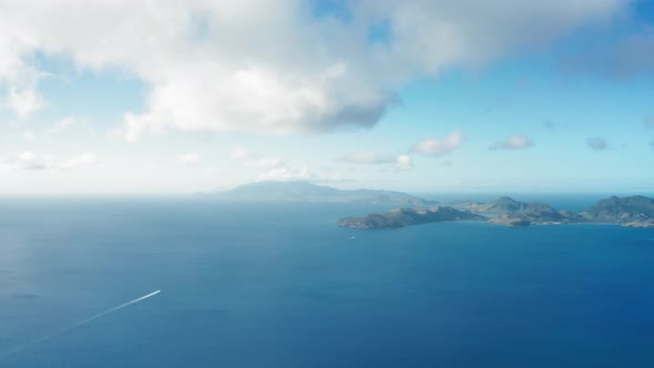 Drone camera shot of two yachts heading towards a hilly island in Saint Kitts and Nevis alt