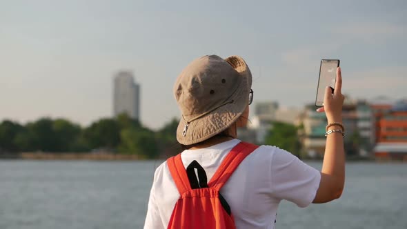 Young Asian women finding networking on mobile beside river location Bangkok Thailand.