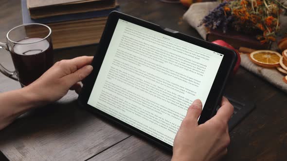 Woman Hand Put on the Table Mug and Start Scrolling Page on Tablet Screen.