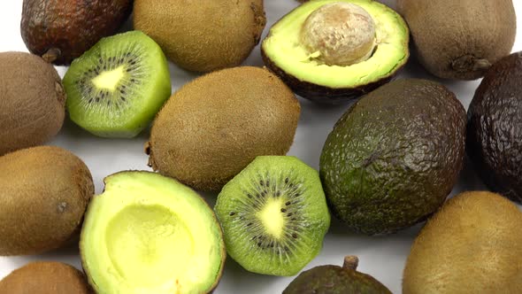 Fruits of avocado and kiwi lie on a white table.