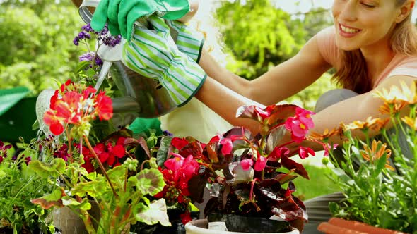 Cute Girl Watering Flowers With Her Mother alt