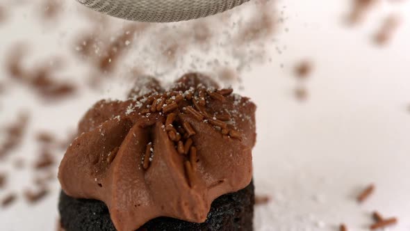 Icing Sugar Being Sieved On Chocolate Cupcake alt