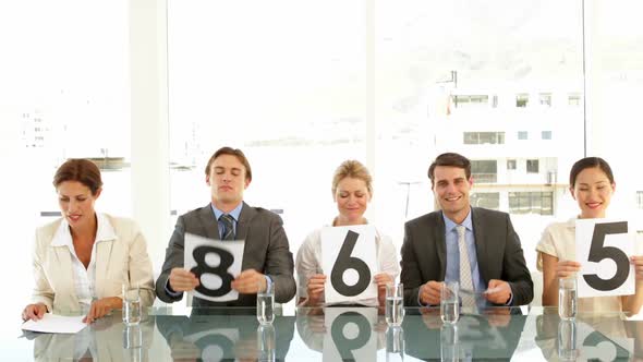 Interview Panel Holding Up Scores And Smiling alt