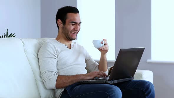 Man Drinking A Coffee While Using A Laptop alt