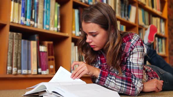 Student Lying On Floor Reading In The Library alt