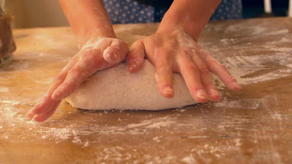 Female Hands Kneading Ball Of Dough On A Floury Surface alt