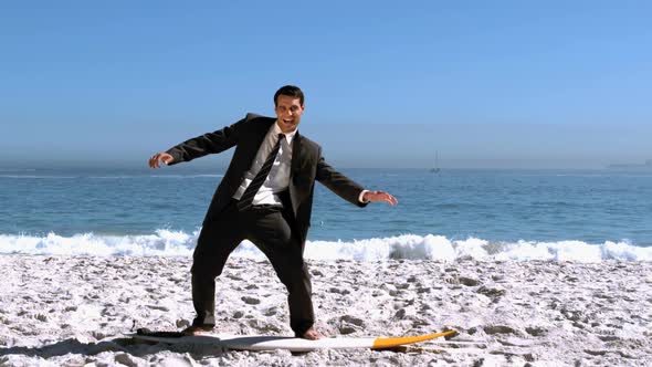 Businessman Balancing On Surfboard On The Beach alt