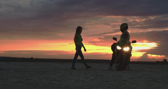 Couple Embracing Near Motorbike on Beach at Sunset