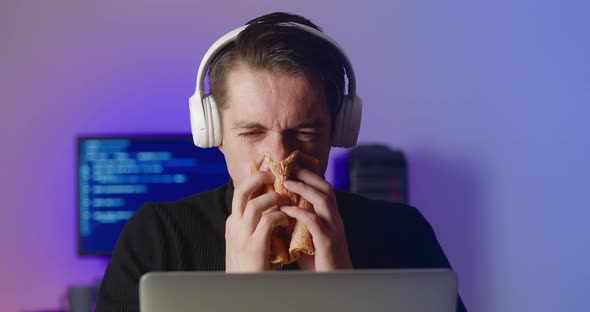 Young Man in Headphones Coughs and Blows His Nose While Working at the Computer alt