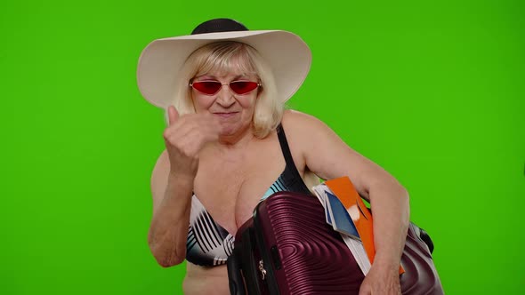 Senior Woman Tourist in Swimsuit with Luggage Passport Tickets Asking to Follow Join on Chroma Key alt