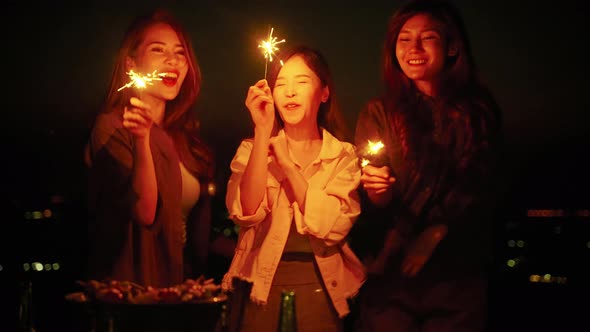 group of young Asian friends are having fun playing fireworks during a summer camping vacation