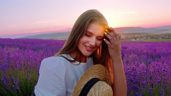 Beautiful Young Woman Wearing White Dress and Hat Standing in a Lavender Field