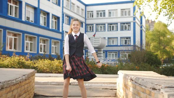 Girl Teenager in School Uniform Dancing in the Street in Front of the School alt