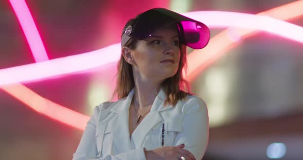 Woman Face with Open Modern Protective Face Shield in Colorful Neon Light of Street Signs alt