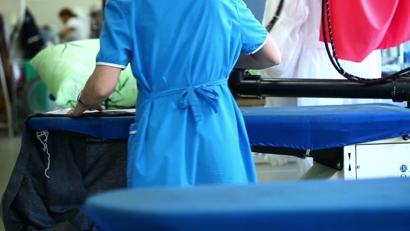 Rear View Of Laundry Worker Ironing Jacket