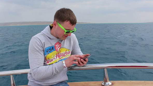 Man with smartphone on yacht