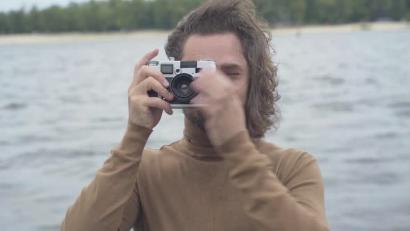 Front View of Happy Smiling Young Man Taking Photo of Camera with Retro Equipment. Portrait of alt