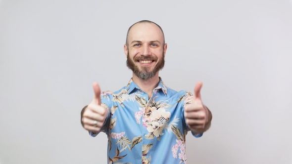 Happy bearded man wearing hawaiian shirt showing thumbs up isolated over white background.