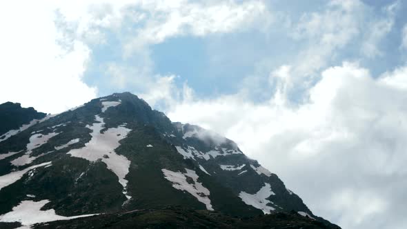 Rapid change of weather and clouds over high snow-capped mountains alt