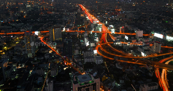 Futuristic night cityscape with traffic across street. Bangkok, Thailand