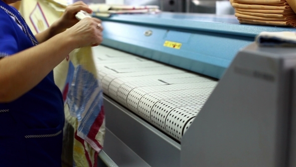 Worker Loads Bedsheet In Ironing Machine
