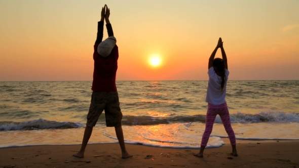 Boy And Girl Making Exercises On The Beach At