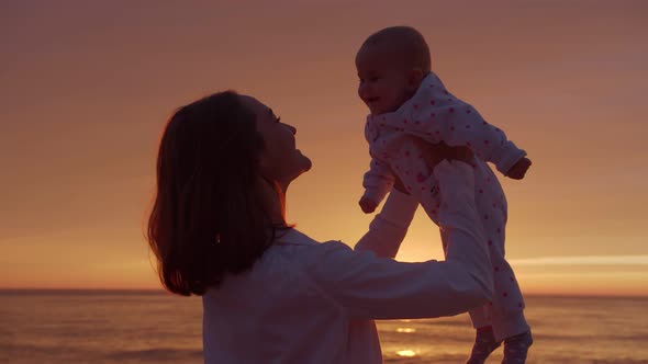Mom hugs baby on a sunset background