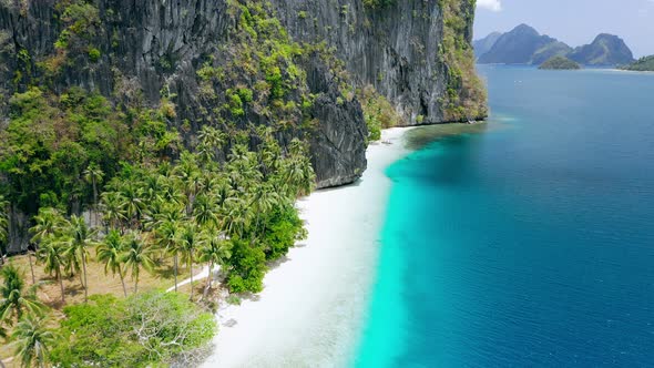 Aerial Drone View of Pristine Tropical White Sand Beach Surrounded By Karst Rocky Cliffs and alt