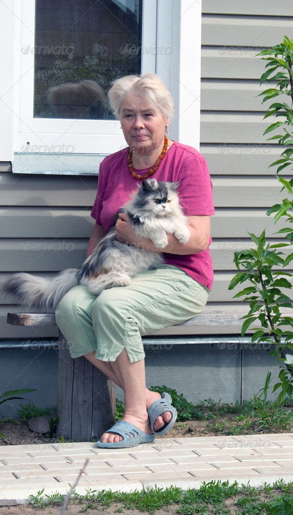 Woman on a summer residence with a cat on hands