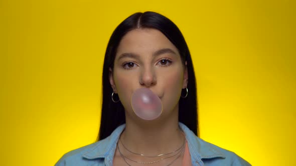 Smiling Woman Blowing and Pop Pink Bubble Gum Candy Looking at Camera