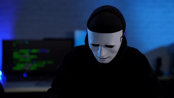 Unrecognizable Hacker in Anonymous Face Mask Raising Hands Up alt