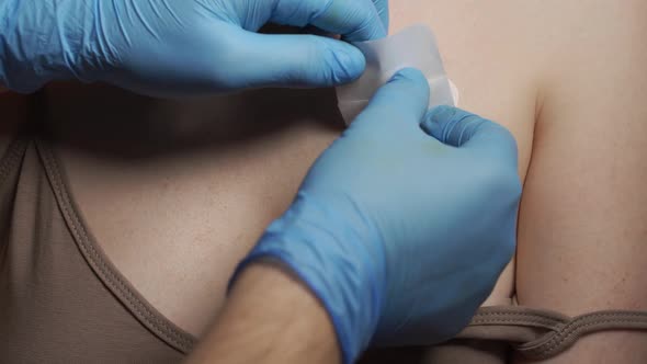 A Doctor in Medical Gloves Glues a Plaster to a Sutured Wound