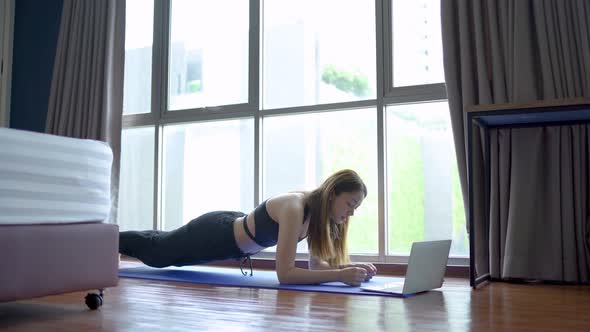 How long can you hold a plank. Young beautiful woman in sportswear doing plank and watching videos  alt